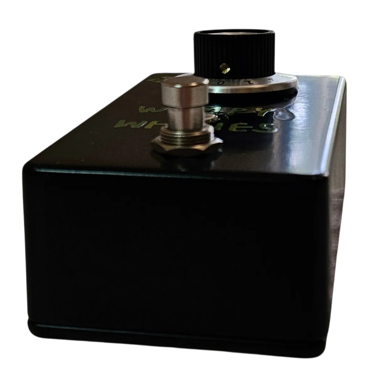 Looking down on the pedal's top edge. The knob and its numbered skirt sit at the near corner, the green lettering is upside down from this angle, and a jack sleeve is visible standing up at the back edge.